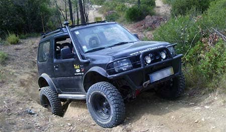 suzuki jimny suspension lift kit in action on a mountain dirt road.