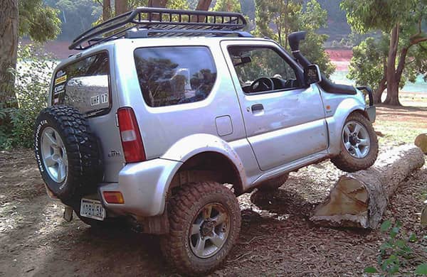 image of silver-suzuki-jimny-off-roading up a fallen tree log